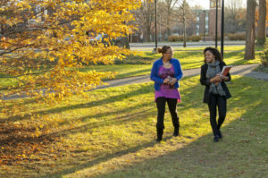 Two students walking Two students Yahaira Murphy and walking next to Carroll Hall at sunset with Clocktower in background.