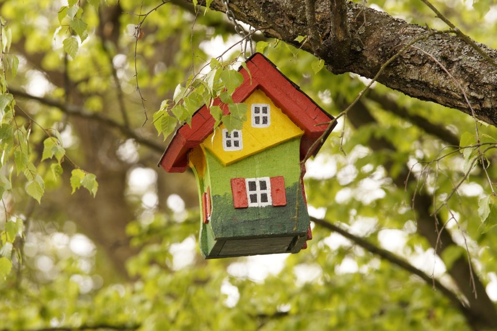 A multicolored birdhouse hanging from a tree