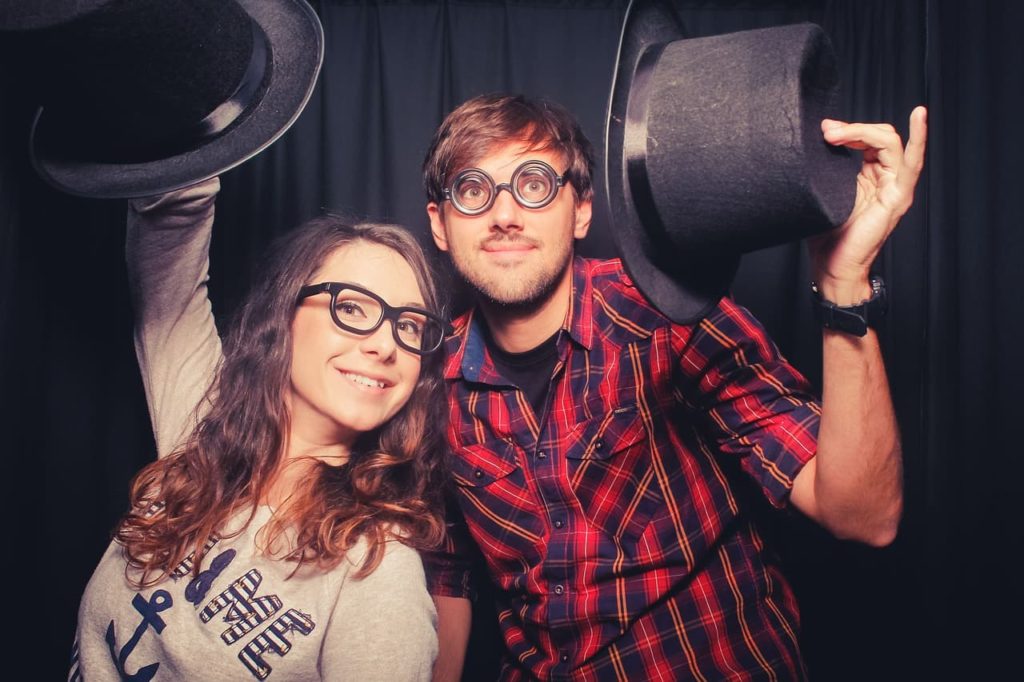 Two "geeky" looking people holding up hats