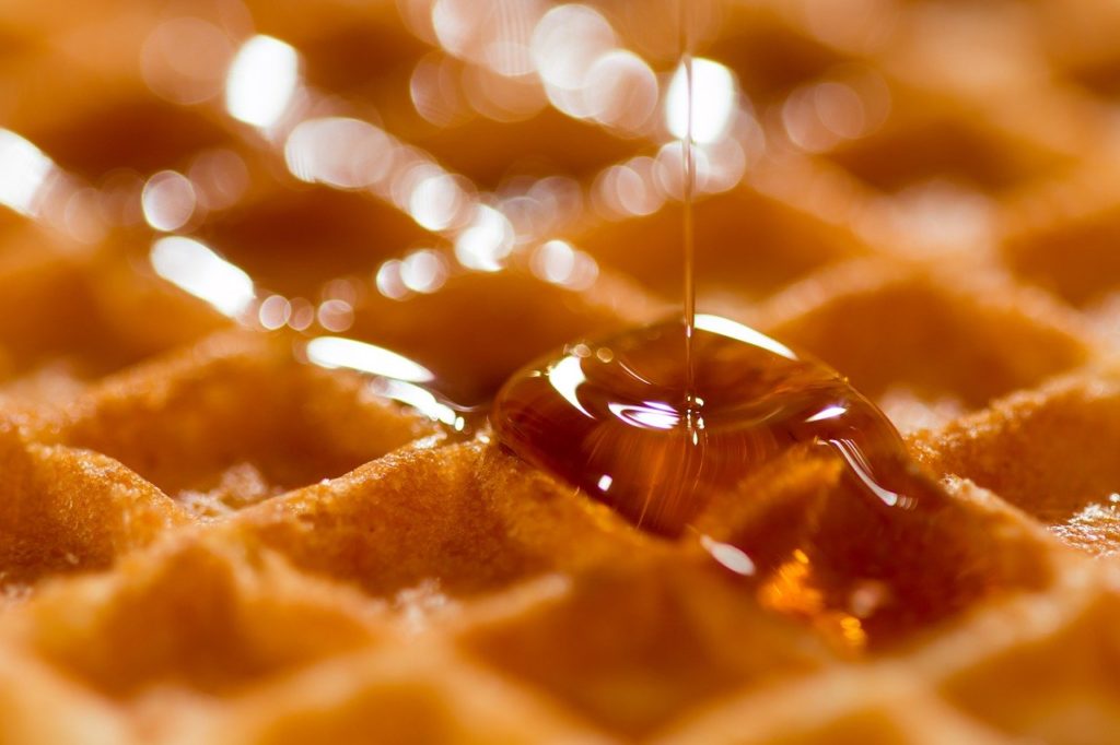 Maple syrup being poured on a waffle