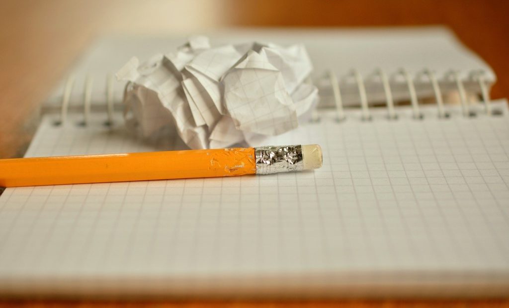 Chewed pencil on a notebook next to a crinkled up piece of paper