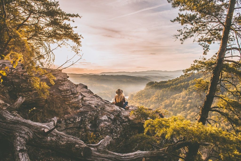 Person sitting on a rock overlooking the earth below