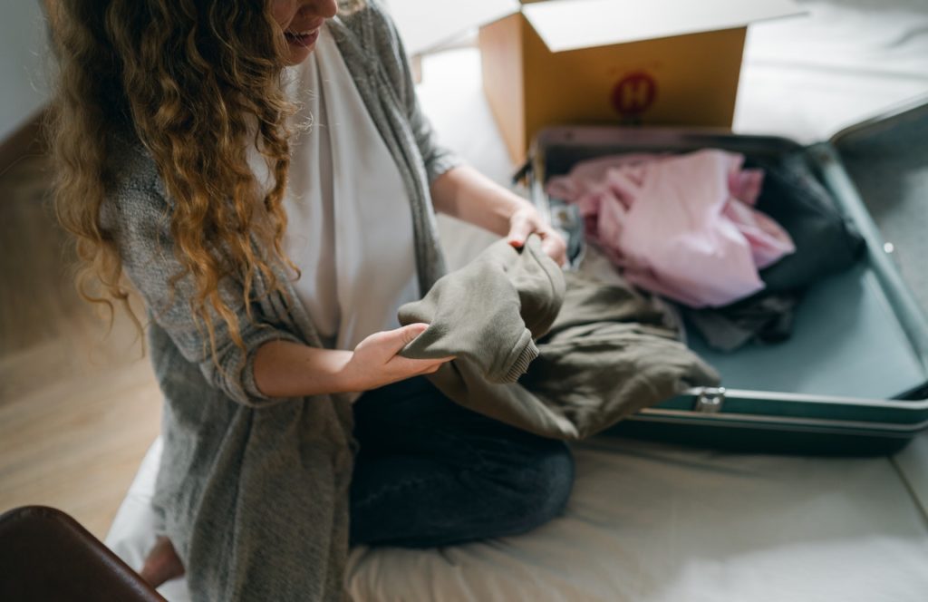 Person on their knees looking at clothing as it is being packed