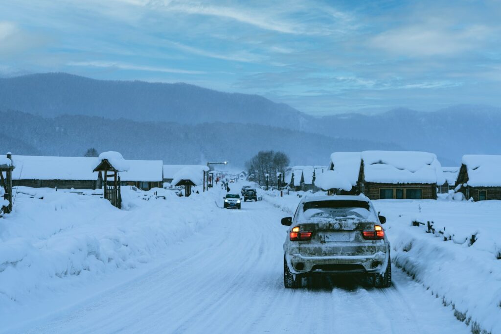 Car driving down a snow-packed road towards a set of mountains.