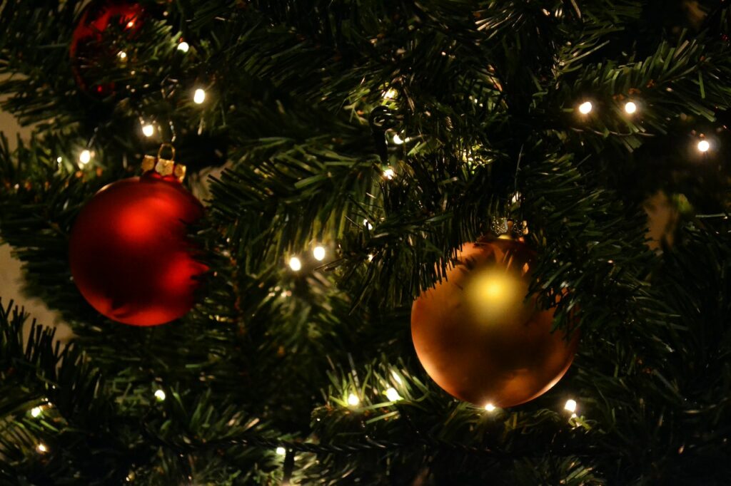 Holiday round bulb ornaments hanging on a lit tree.