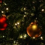 Holiday round bulb ornaments hanging on a lit tree.