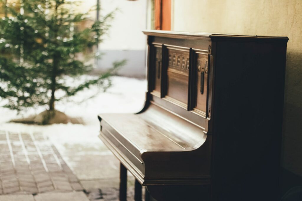 An upright piano set against a wall, facing the left.