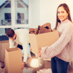 Wife wearing warm sweater holding box while moving in new house