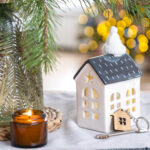 A festive table with a small house shaped candle holder with a key next to it.