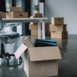 cardboard box with folders and office supplies on floor during relocation