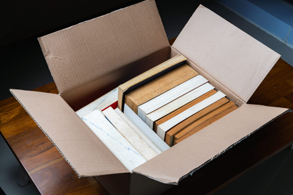 A stack of old books stored in a cardboard box