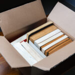 A stack of old books stored in a cardboard box
