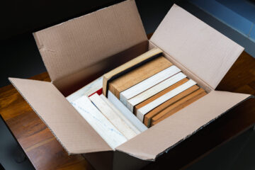 A stack of old books stored in a cardboard box